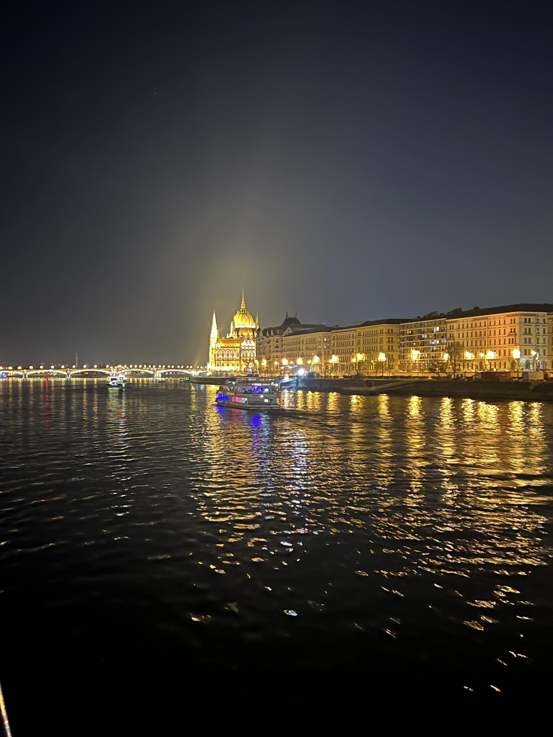 Luxury river cruise ship sailing past Budapest’s illuminated Hungarian Parliament building at night, showcasing iconic landmarks and vibrant cityscape—perfect representation of 2026 travel trends in immersive and elegant river cruising