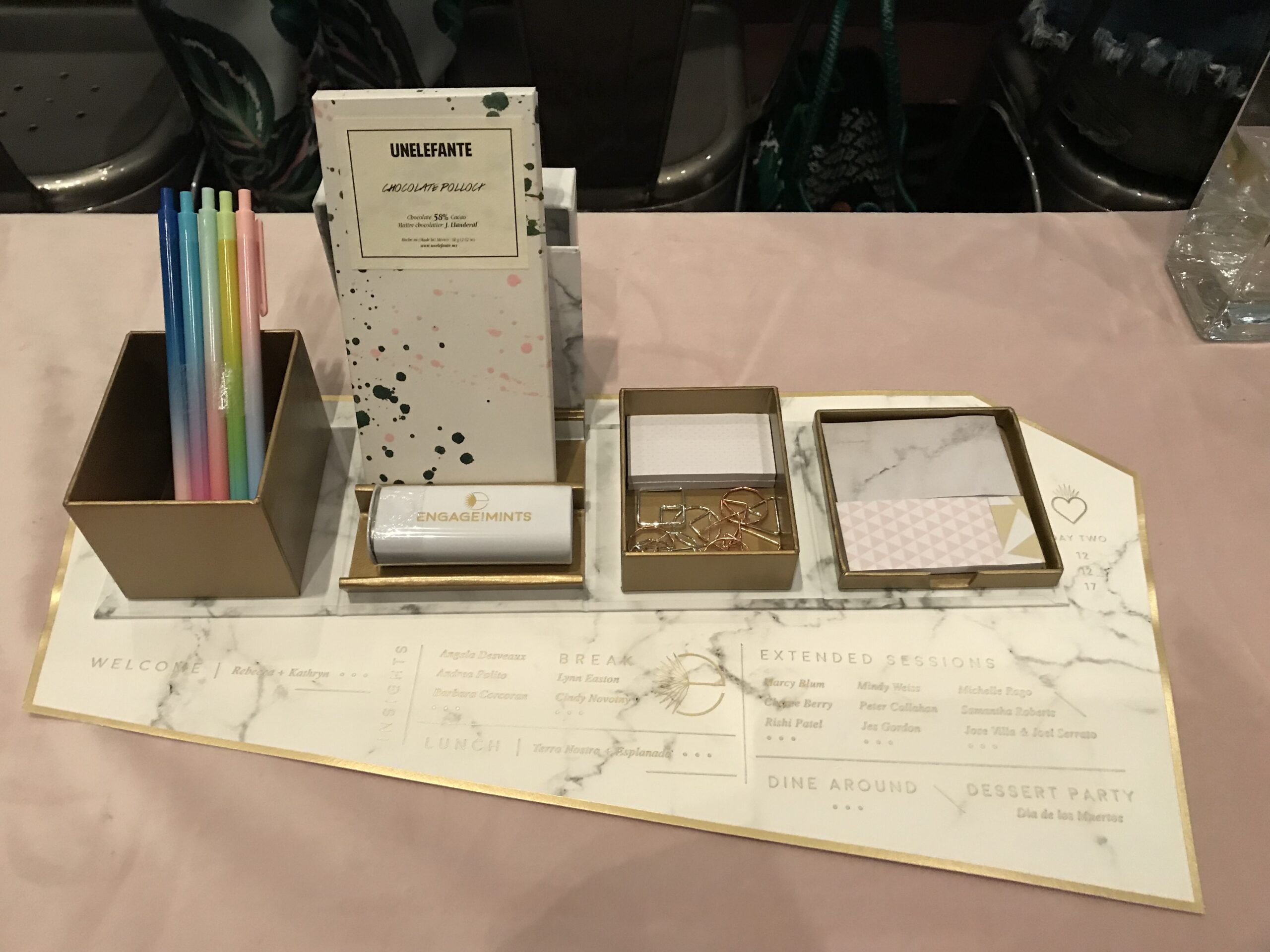 Curated group trip welcome gifts flatlay including travel journal, pen, chapstick, moisturizer, local snacks